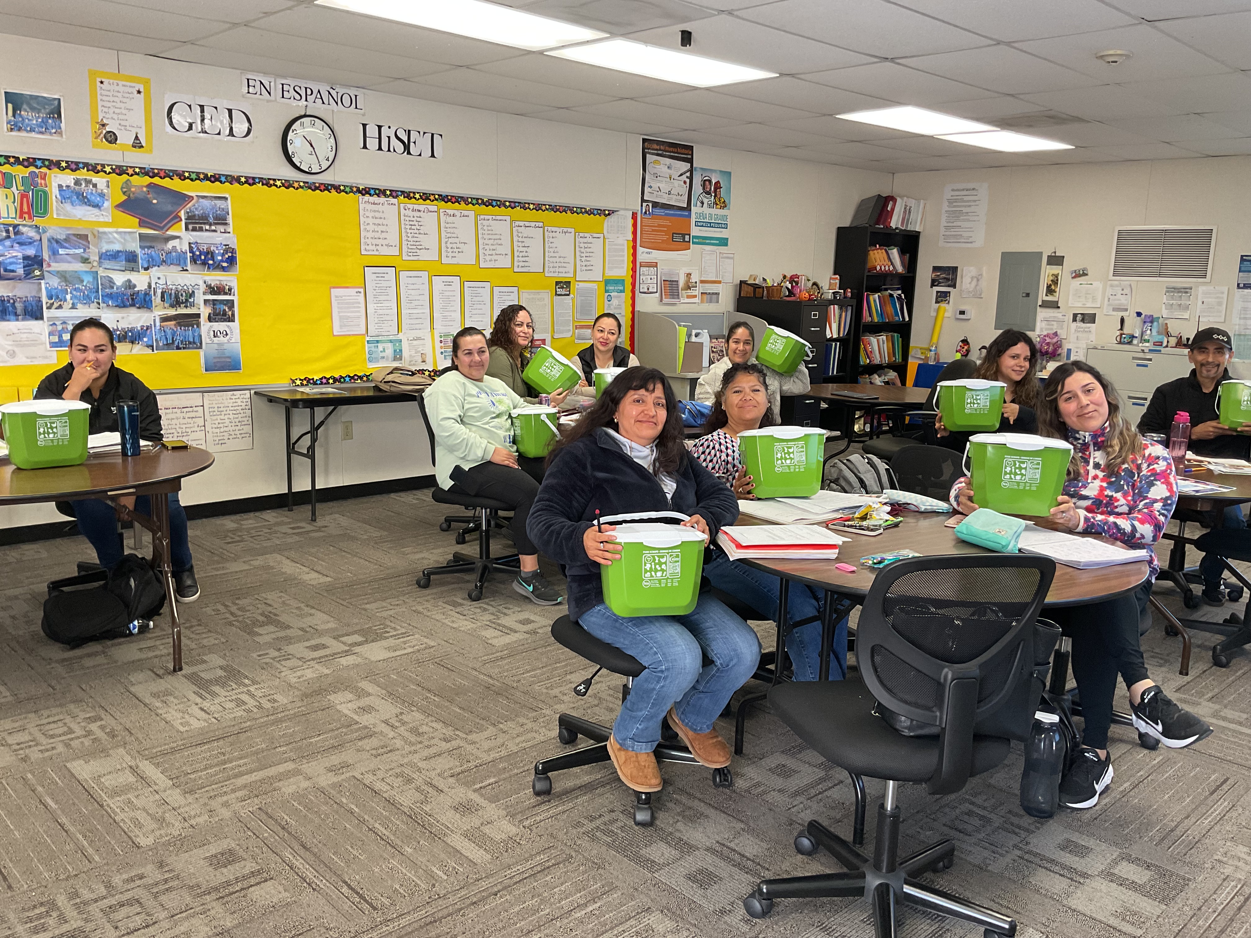People in a class room holding up compost bins